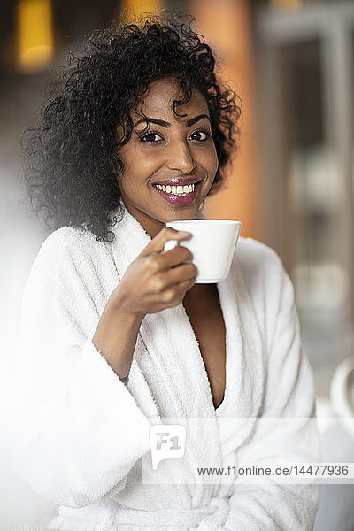 Porträt einer lächelnden jungen Frau beim Kaffeetrinken im Spa