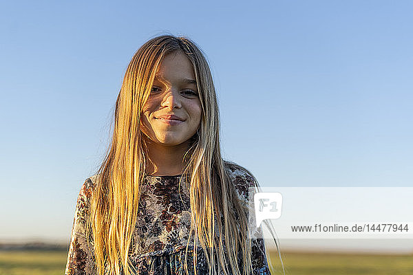 Porträt eines lächelnden blonden Mädchens bei Sonnenuntergang