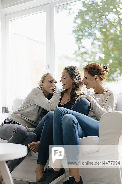 Glückliche Mutter mit zwei Teenager-Mädchen auf der Couch zu Hause