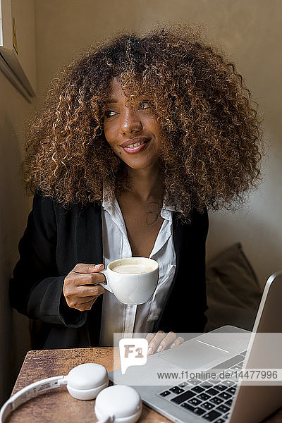 Junge Frau mit Laptop in einem Café  die einen Kaffee trinkt