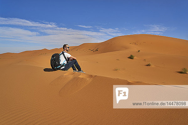 Marokko  Mann sitzt auf Wüstendüne und schaut auf Aussicht