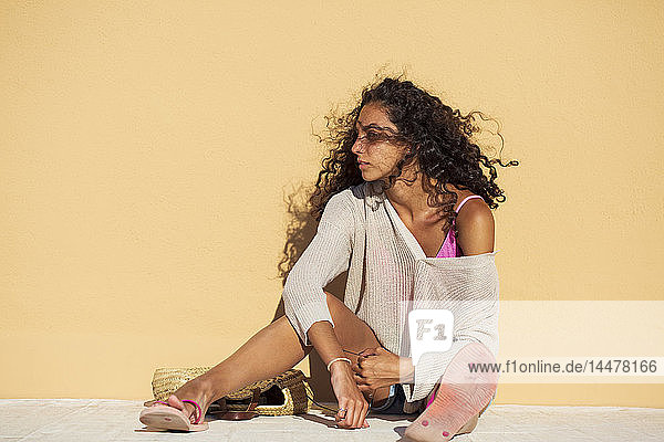 Porträt einer Teenagerin auf oranger Wand sitzend