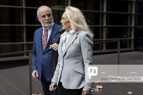 Senior businessman and businesswoman walking and talking in a foyer