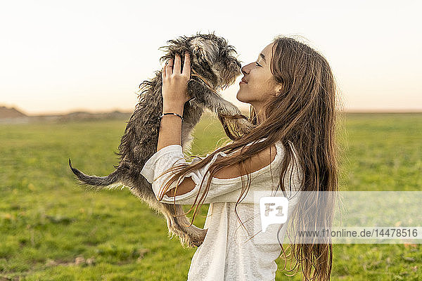 Lächelndes Mädchen kuschelt Hund im Freien