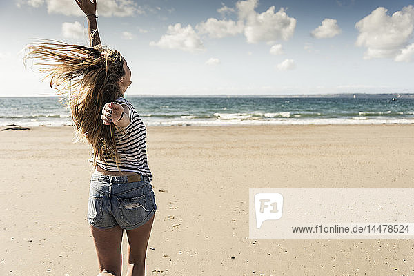 Glückliche junge Frau tanzt am Strand
