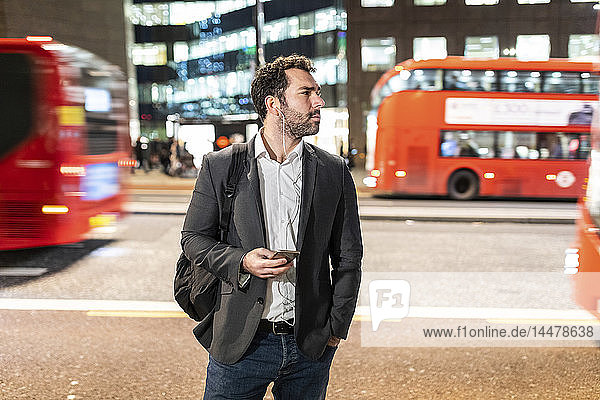 UK  London  Geschäftsmann steht nachts an einer belebten Straße