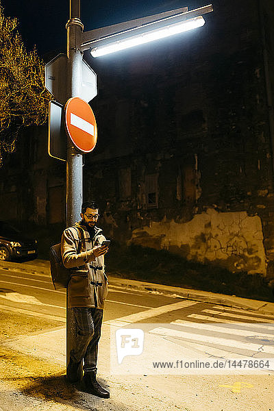 Spanien  Igualada  Mann steht nachts unter einer Straßenlaterne und benutzt ein Mobiltelefon