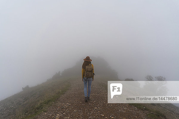 Woman hiking in the fog  walking on a mountain path