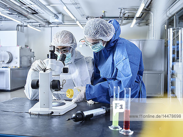Chemiker  die im Industrielabor arbeiten  Schutzkleidung tragen  Mikroskop benutzen