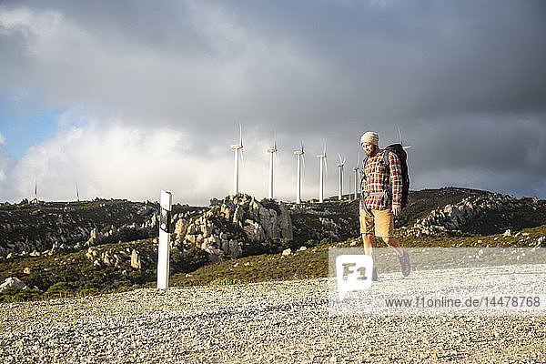 Spanien  Andalusien  Tarifa  Mann auf einer Wanderung auf einem Feldweg mit Windturbinen im Hintergrund