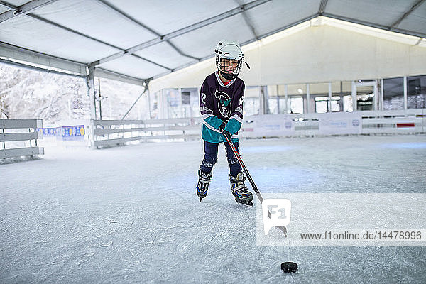 Boy playing ice hockey on the ice rink