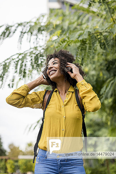 Glückliche Frau  die im Freien mit Kopfhörern Musik hört