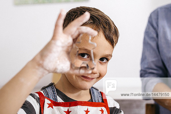 Porträt eines lächelnden kleinen Jungen  der durch eine Keksdose schaut
