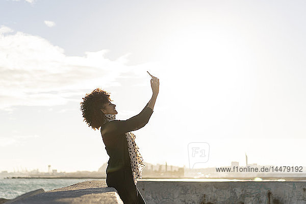 Lächelnde Frau mit Smartphone am Meer