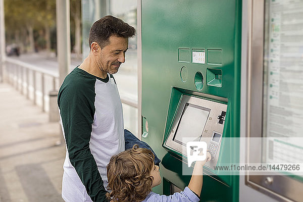 Vater und Sohn benutzen den Fahrkartenautomaten an der Straßenbahnhaltestelle in der Stadt
