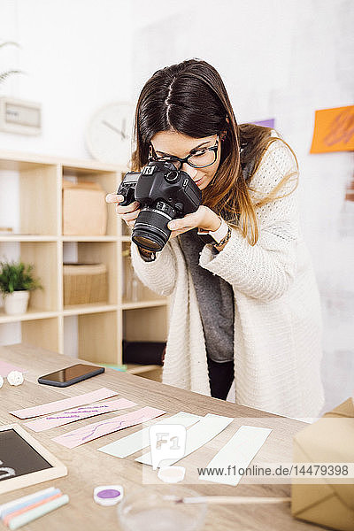 Young woman taking pictures with a camera for her craft blog
