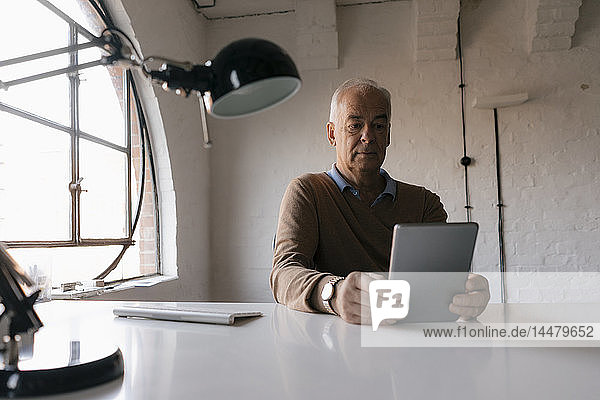 Senior businessman using tablet at desk in office