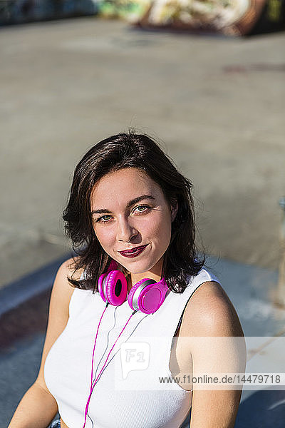 Porträt einer lächelnden jungen Frau mit Kopfhörern in der Stadt