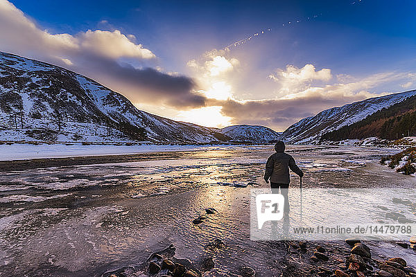 United Kingdom  Scotland  Highlands  female hiker standing at icy riverside