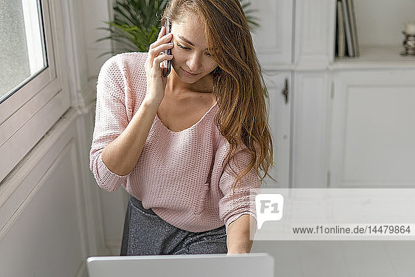 Young businesswoman  using laptop  talking on the phone