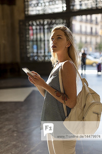 Junge Frau mit Handy und Rucksack in der Stadt