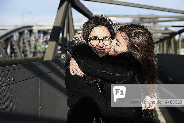 Glückliche Freunde  die sich auf einer Brücke umarmen