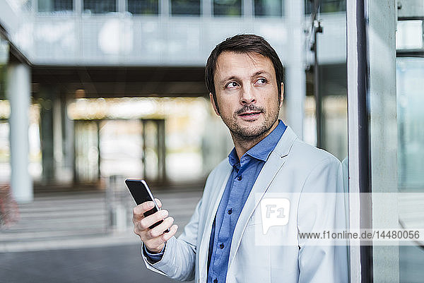 Portrait of a businessman using smartphone in the city