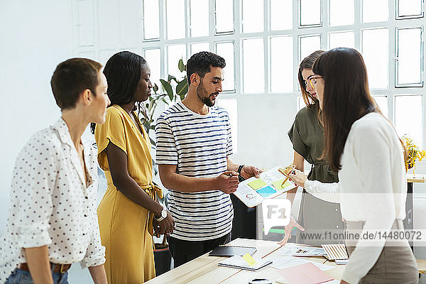 Colleagues working together at desk in office discussing papers