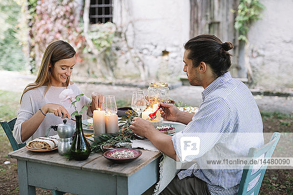 Paar beim romantischen Essen bei Kerzenlicht neben einer Hütte