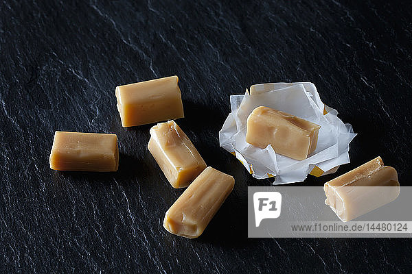 Sahnebonbons und Geschenkpapier auf schwarzem Schiefer