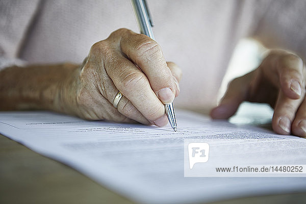 Die Hand einer älteren Frau  die ein Dokument unterzeichnet  Nahaufnahme