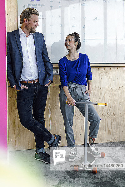 Mature man and his assistent with scooter  standing in office in front of white board