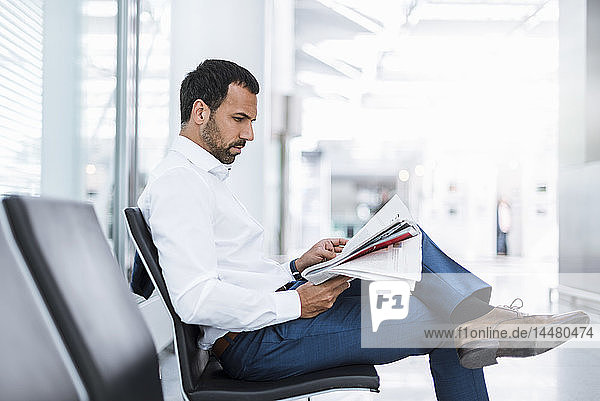 Geschäftsmann liest eine Zeitung im Wartesaal