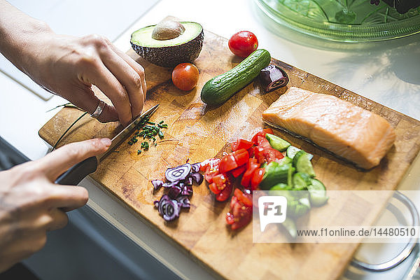 Woman preparing vegetables and salmon on chopping board