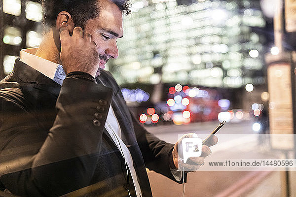 UK  London  businessman on the go checking his phone while commuting by night