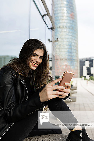 Spanien Barcelona  lächelnde junge Frau mit Handy in der Stadt
