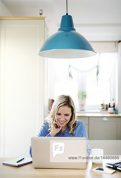 Lächelnde Frau mit Laptop bei der Arbeit zu Hause