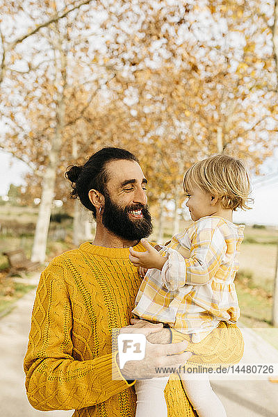 Vater trägt seine Tochter an einem Morgen im Herbst im Park