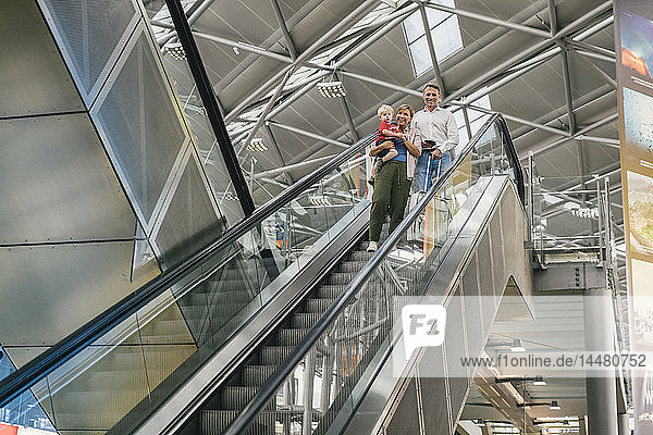 Glückliche Familie auf der Rolltreppe am Flughafen