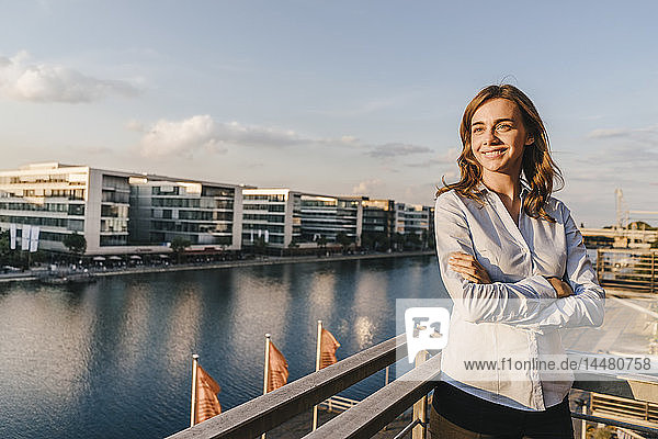 Geschäftsfrau steht auf der Terrasse eines Industriegebäudes