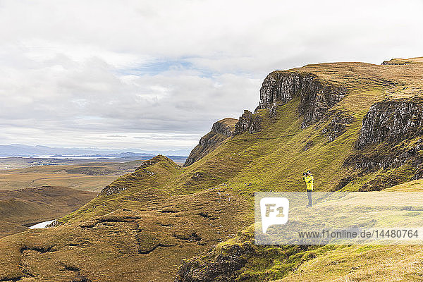 UK  Scotland  Isle of Skye  Quiraing  photographer on top of a cliff taking photos