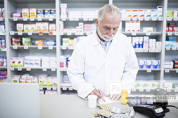Pharmacist with medicine at counter in pharmacy
