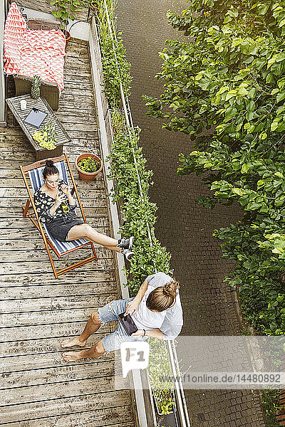 Junges Paar entspannt sich im Sommer auf ihrem Balkon