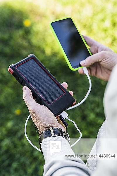 Businessman charging his smartphone with a solar power bank
