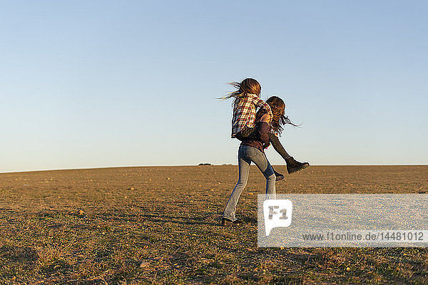 Mädchen nimmt ihre Schwester huckepack ins Freie mit