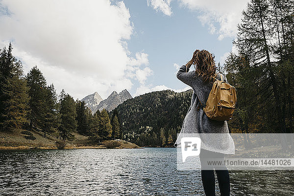 Switzerland  Grisons  Albula Pass  woman on a hiking trip standing at lakeside in mountainscape