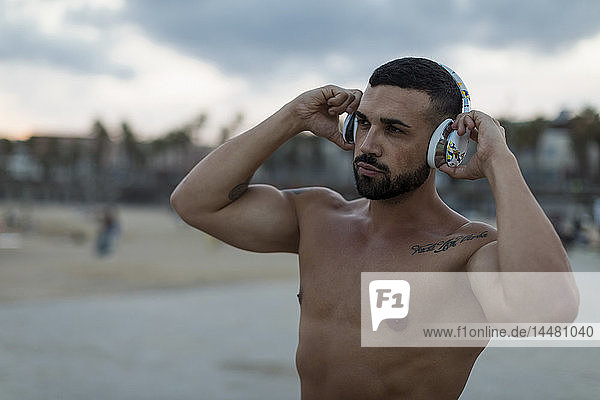 Porträt eines barbusigen  muskulösen Mannes mit Kopfhörern im Freien