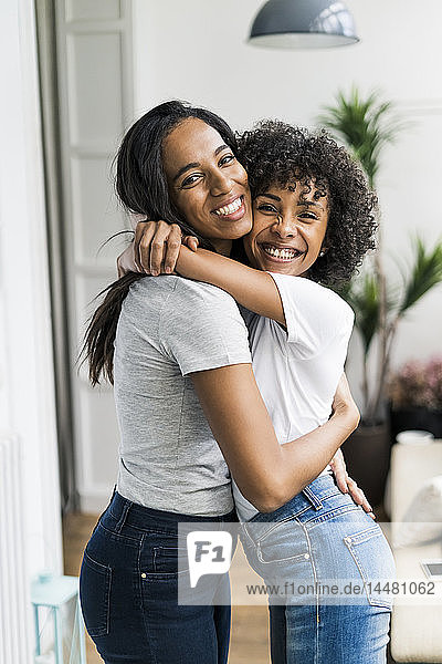 Porträt von zwei glücklichen Freundinnen  die sich zu Hause umarmen