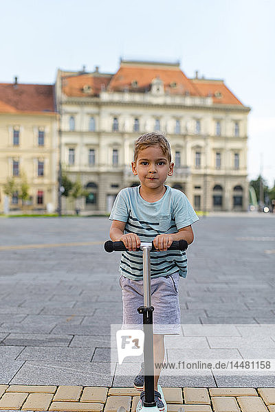 Porträt eines Jungen auf einem Roller in der Stadt