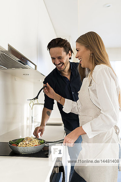 Glückliches Paar bereitet in seiner Küche Spaghetti zu